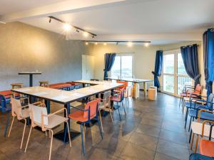 un comedor con mesas, sillas y ventanas en ibis Budget Millau Viaduc en Millau