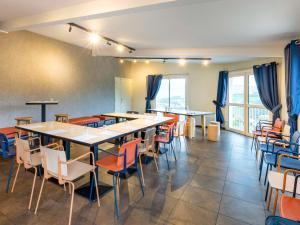 a dining room with tables and chairs and windows at ibis Budget Millau Viaduc in Millau