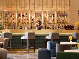 曼谷Mövenpick Hotel Bangkok Ploenchit BDMS的站在餐厅酒吧后面的人