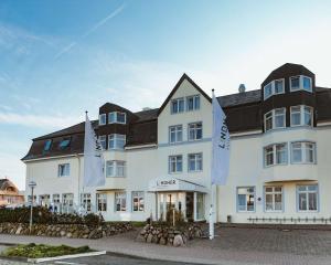 um grande edifício branco com bandeiras à frente em Lindner Hotel Sylt em Wenningstedt