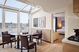 デュッセルドルフにあるLindner Hotel Dusseldorf Airport, part of JdV by Hyattのテーブルと椅子のあるキッチンとダイニングルーム