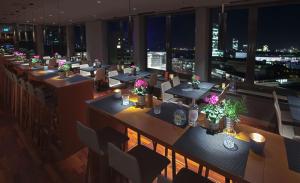 a restaurant with tables and chairs with a view of the city at me and all hotel Dusseldorf, part of JdV by Hyatt in Düsseldorf