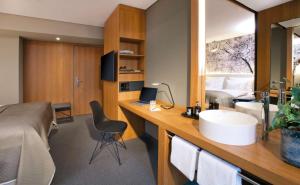 a bedroom with a bed and a desk with a sink at me and all hotel Dusseldorf, part of JdV by Hyatt in Düsseldorf