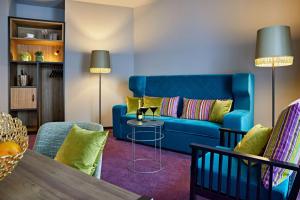 uma sala de estar com um sofá azul e uma mesa em me and all hotel Dusseldorf Oberkassel, part of JdV by Hyatt em Dusseldorf