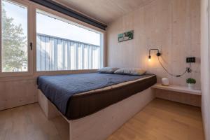 Bett in einem Zimmer mit einem großen Fenster in der Unterkunft BUQEZ VILLAS - VILLA 31 in Drage