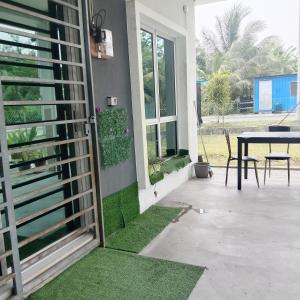 een patio met een tafel en een raam met gras bij Homestay Lestari KLIA in Sepang