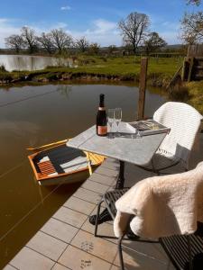 uma mesa com uma garrafa de vinho e dois copos em Waters edge em Cucklington