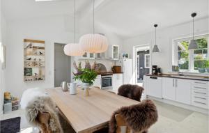 Una cocina con una mesa de madera con tres perros sentados alrededor de ella. en 3 Bedroom Awesome Home In Græsted, en Græsted