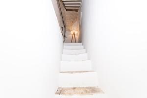 una escalera en un edificio blanco con una lámpara en Dimora del Vico - Exclusive Terrace with View, en Cisternino
