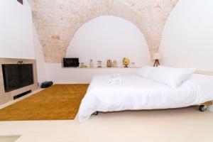 a bedroom with a white bed and a tv at Dimora del Vico - Exclusive Terrace with View in Cisternino
