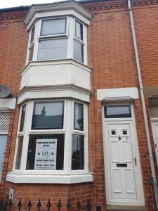 - un bâtiment en briques avec une fenêtre et une porte blanche dans l'établissement 2 bedroom house - Hopefield Road, à Leicester