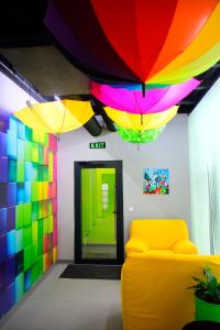 Green Cube Capsule Hostel في صوفيا: غرفة مع أريكة صفراء ومظلات ملونة