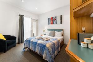 a bedroom with a bed with a blue checked blanket at The Hidden Gem - Adelaide CBD in Adelaide