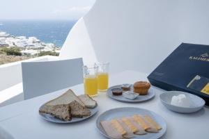 a table with plates of food and a box of orange juice at Feel Breeze in Mýkonos City