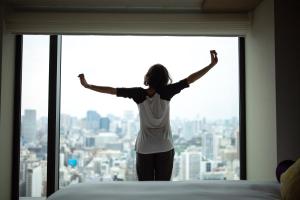 a woman standing in front of a window with her arms up at THE BLOSSOM HIBIYA in Tokyo