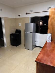 a kitchen with a refrigerator and a trash can at Axe Apartments in Solwezi
