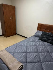 1 dormitorio con 1 cama y armario de madera en Axe Apartments, en Solwezi