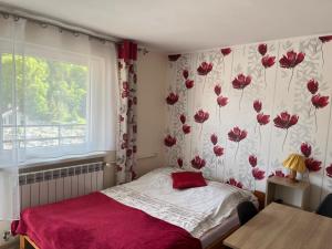a bedroom with a bed and a window with red flowers at Willa Safra Szczawnica in Szczawnica