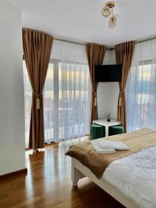 a bedroom with a bed and a table and windows at Silver Mountain Villa Colibita in Colibiţa