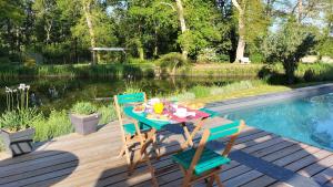 een tafel en stoelen op een terras naast een zwembad bij Le Moulin de Saubrigues in Saubrigues