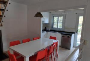 タラゴナにあるCasa de los Pinos Cala La Moraのキッチン(白いテーブル、赤い椅子付)