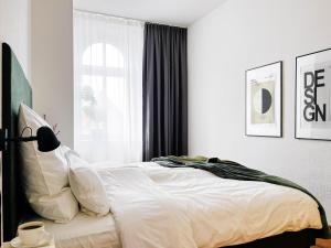 a bedroom with a bed with white sheets and a lamp at MOKA Living-Sunset Apt, Nordic Design,Küche,WLAN, SmartTV in Magdeburg