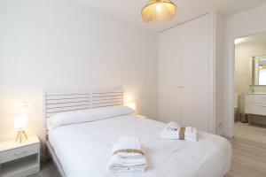 a bedroom with a white bed with two towels on it at Global Properties, Moderno apartamento a 3 minutos de la playa in Puerto de Sagunto