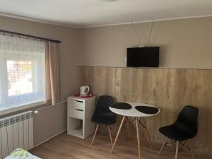 シュツァブニツァにあるWilla Safra Szczawnicaのテーブルと椅子、壁にテレビが備わる客室です。