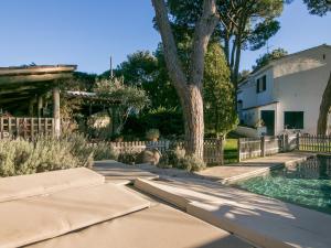 a swimming pool with two umbrellas next to a house at VILLA CANADELL - great garden, 5 min to beach in Palafrugell