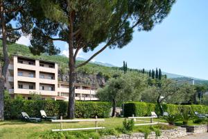 a building with trees and chairs in a park at Residence Lido Hotel in Malcesine