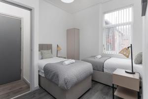 a white bedroom with two beds and a window at Newly Renovated Apartments in Liverpool - Extended Stay in Liverpool