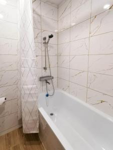 a white bath tub in a bathroom with marble walls at Vasaros estrados apartamentai, self check-in, free parking in Klaipėda +16 photos