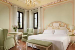 una camera con un letto bianco e due sedie verdi di Relais Villa Monte Solare Wellness & SPA a Panicale