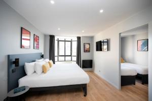 パリにあるStaycity Aparthotels Paris Gare de l'Estのベッドルーム1室(ベッド2台、鏡付)