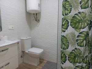 a bathroom with a toilet and a green leafy shower curtain at Bazan Apartaments2 in Alicante +13 photos