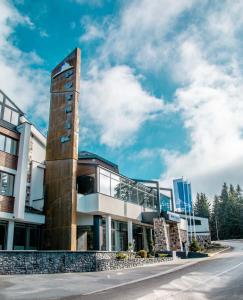 a building with a tower on the side of a street at Hotel Putnik Kopaonik in Kopaonik