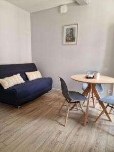 een woonkamer met een blauwe bank en een tafel bij Appartement au coeur de Vezelay - GALERIE 10 in Vézelay