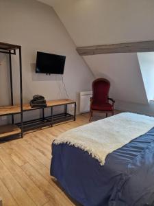 a bedroom with a bed and a tv and a chair at Appartement au coeur de Vezelay - GALERIE 10 in Vézelay