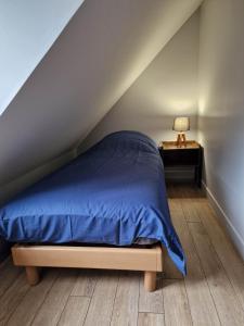 a bedroom with a bed with a blue comforter and a table at Appartement au coeur de Vezelay - GALERIE 10 in Vézelay
