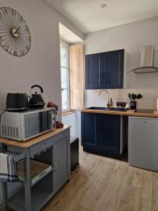 a kitchen with blue cabinets and a microwave at Appartement au coeur de Vezelay - GALERIE 10 in Vézelay