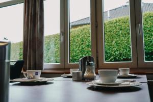 a table with cups and saucers on it with windows at Appartement Steinbichler in Graz