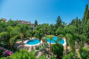 an aerial view of a resort with two pools and palm trees at Modern and Spacious 2 BDRM Penthouse - 3 Pools and Sea Views in Marbella