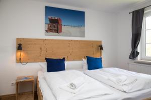 a bedroom with two beds with white sheets and blue pillows at Wattlodge in Norden