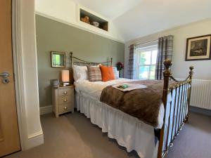 ein Schlafzimmer mit einem Bett mit orangefarbenen Kissen und einem Fenster in der Unterkunft Downton Lodge Country Bed and Breakfast and; Self Catering in Dartmouth