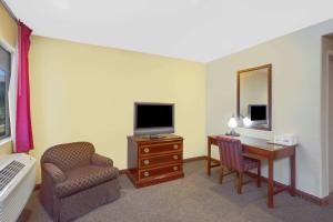 Habitación de hotel con escritorio, TV y silla en Baymont by Wyndham Coalinga, en Coalinga