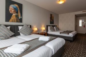 a room with two beds and a painting of a woman at Amsterdam Hotel Uithoorn in Uithoorn