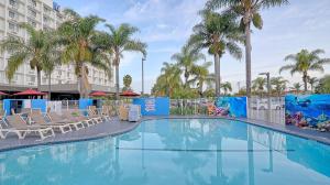 uma piscina num hotel com cadeiras e palmeiras em Suites Los Angeles CA Los Angeles LAX em Inglewood