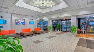 a lobby with orange chairs and plants in a building at Suites Los Angeles CA Los Angeles LAX in Inglewood
