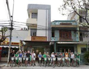 een groep mensen op de fiets voor een gebouw bij Kiman Old Town Hotel in Hội An