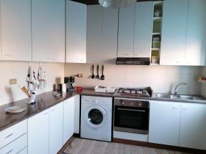 a kitchen with white cabinets and a washing machine at Appartamenti I Mulini in Trapani